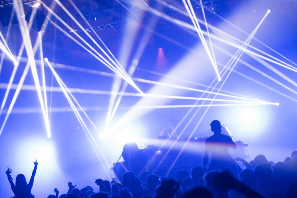 Crowd dancing beneath colorful lights at an electronic music event